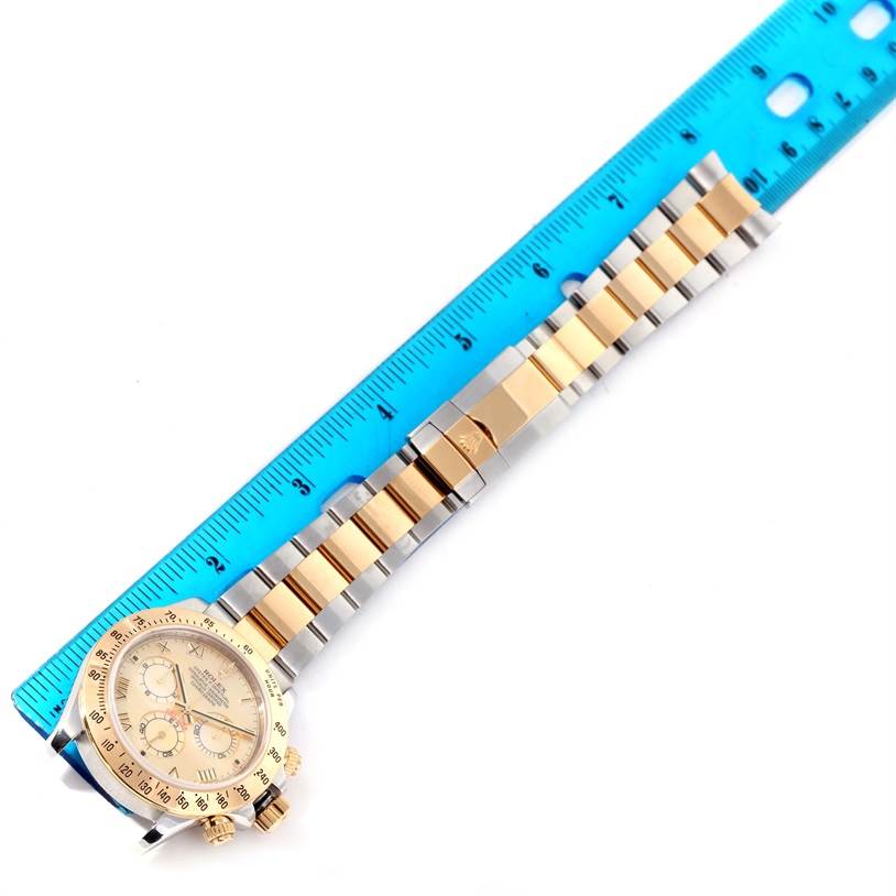 The image shows a Rolex Daytona 116523 Men's Steel and Gold (two tone) Mother of Pearl Dial 116523 Men's Steel and Gold (two tone) Mother of Pearl Dial watch laid flat with a blue ruler measuring the length of its gold and silver bracelet.