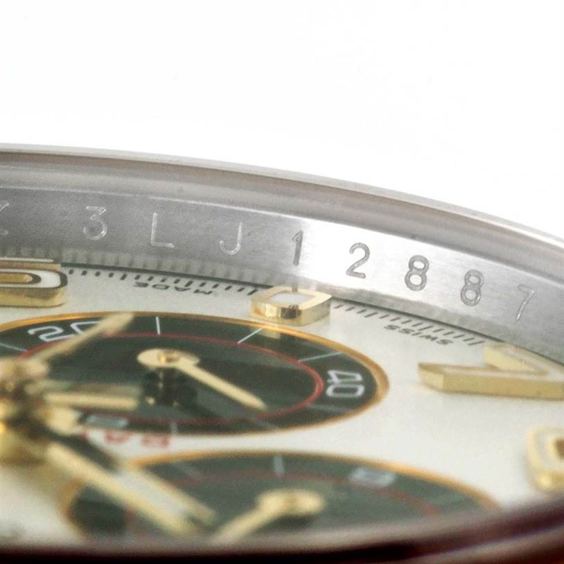 This image shows a close-up of the dial and part of the bezel of a Rolex Daytona 116523 Men's Steel and Gold (two tone) White Dial 116523 Men's Steel and Gold (two tone) White Dial watch at an angle.