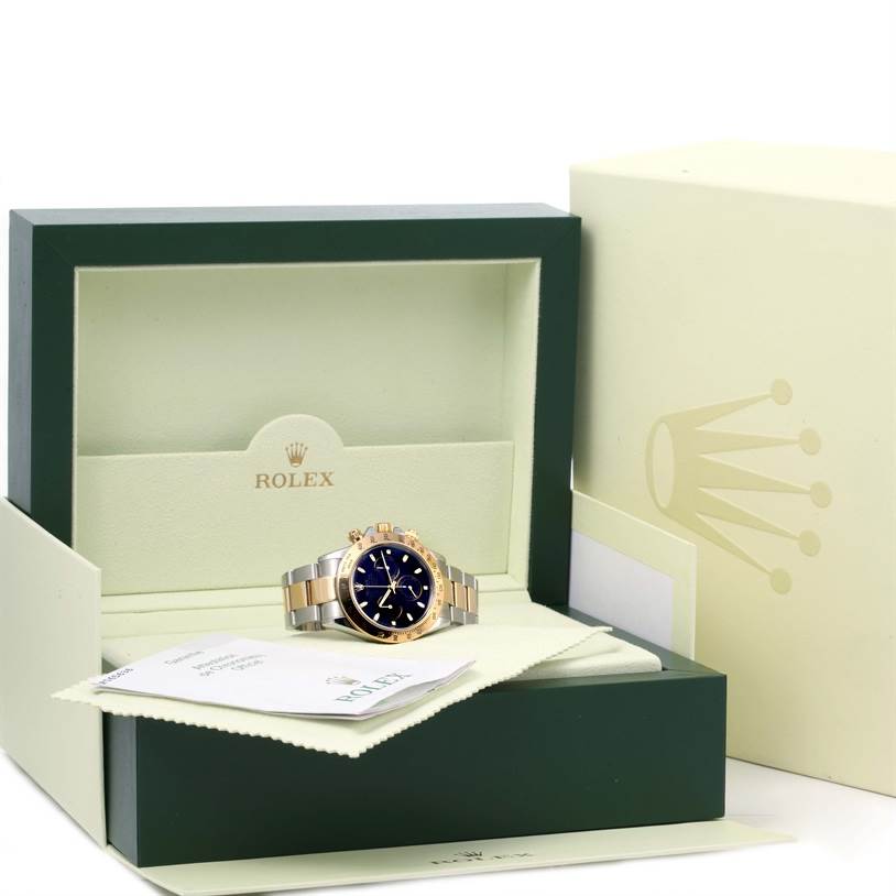 The Rolex Daytona 116523 Men's Steel and Gold (two tone) Black Dial 116523 Men's Steel and Gold (two tone) Black Dial watch is shown in a front-facing angle inside an open green box, with paperwork and accessories.