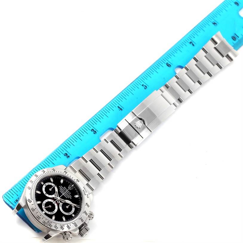 The Rolex Daytona 116520 Men's Stainless Steel Black Dial 116520 Men's Stainless Steel Black Dial watch is shown with a close-up on its face and metal bracelet, alongside a ruler for scale.