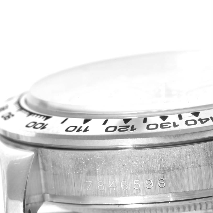 The image shows a close-up angled side view of a Rolex Daytona 116509 Men's White Gold Silver Dial 116509 Men's White Gold Silver Dial model, focusing on the bezel and part of the case with the serial number visible.