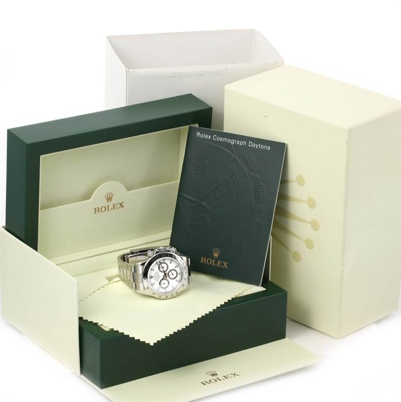 The image shows a Rolex Daytona 116520 Men's Stainless Steel White Dial 116520 Men's Stainless Steel White Dial watch in a green and cream presentation box, along with documentation and a cleaning cloth.