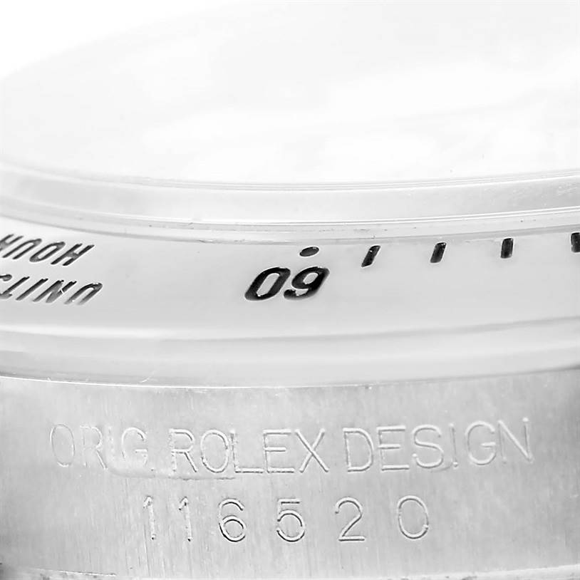 This close-up image shows the bezel and engraved case side of a Rolex Daytona 116520 Men's Stainless Steel White Dial 116520 Men's Stainless Steel White Dial model watch.