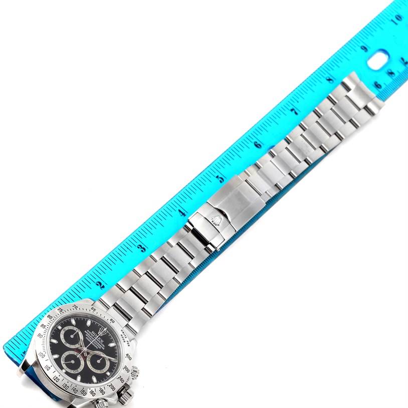 The image shows a flat, overhead view of a Rolex Daytona 116520 Men's Stainless Steel Black Dial 116520 Men's Stainless Steel Black Dial watch with a ruler measuring the length of its metal bracelet.