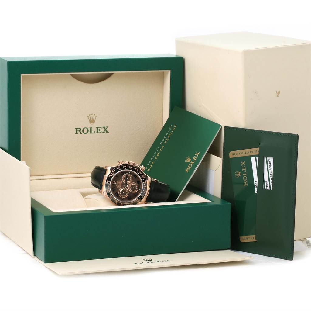 The image shows a Rolex Daytona 116515LN Men
s Rose Gold Brown Dial 116515LN Men
s Rose Gold Brown Dial watch in its box, along with warranty cards and a booklet.