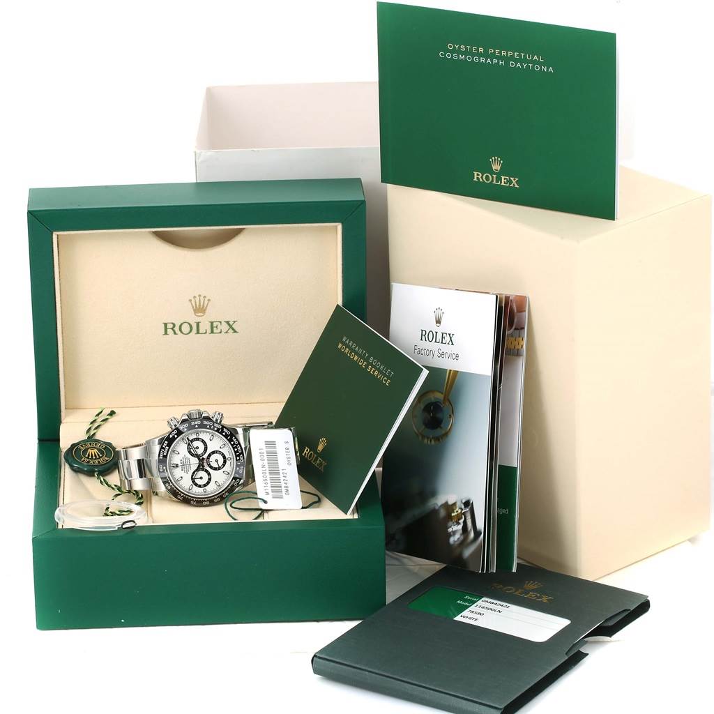 The image shows a Rolex Daytona 116500 Men's Stainless Steel White Dial 116500 Men's Stainless Steel White Dial watch and its accessories, including manuals, a tag, and the box, from a front angle.