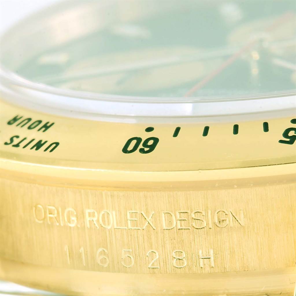 The image shows a close-up of the bezel and engraved case of a Rolex Daytona 116528 Men's Yellow Gold Black Dial 116528 Men's Yellow Gold Black Dial watch.