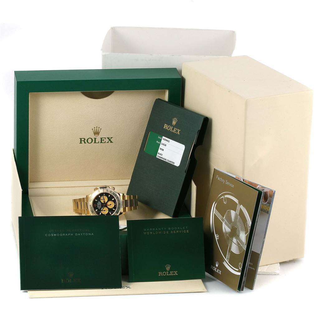 This image shows a Rolex Daytona 116528 Men's Yellow Gold Black Dial 116528 Men's Yellow Gold Black Dial watch in its box with warranty cards, booklets, and service papers arranged around it.