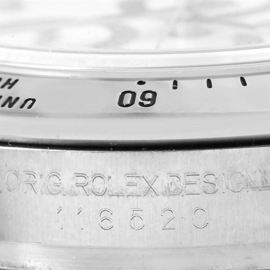 This image shows a close-up of the bezel and the engraved case side of a Rolex Daytona 116520 Men's Stainless Steel White Dial 116520 Men's Stainless Steel White Dial watch.