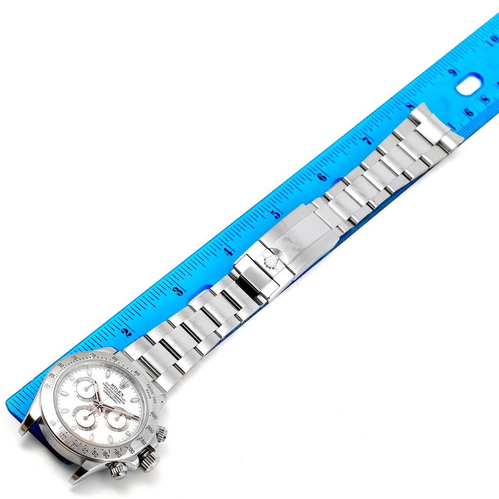 The Rolex Daytona 116520 Men's Stainless Steel White Dial 116520 Men's Stainless Steel White Dial watch is shown from above with its face, bezel, and bracelet next to a ruler for measurement.