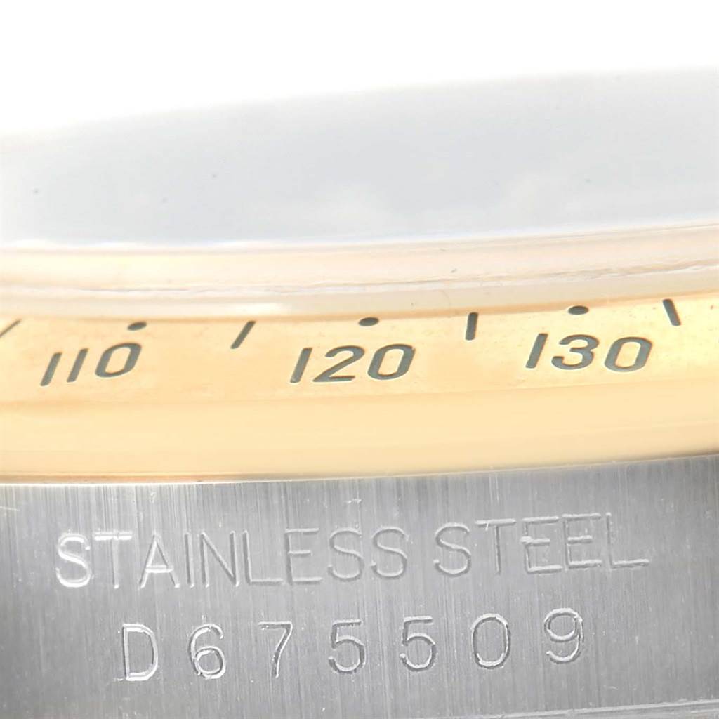 The close-up image shows part of the bezel and the stainless steel case with the serial number of a Rolex Daytona 116523 Men's Steel and Gold (two tone) Black Dial 116523 Men's Steel and Gold (two tone) Black Dial watch.