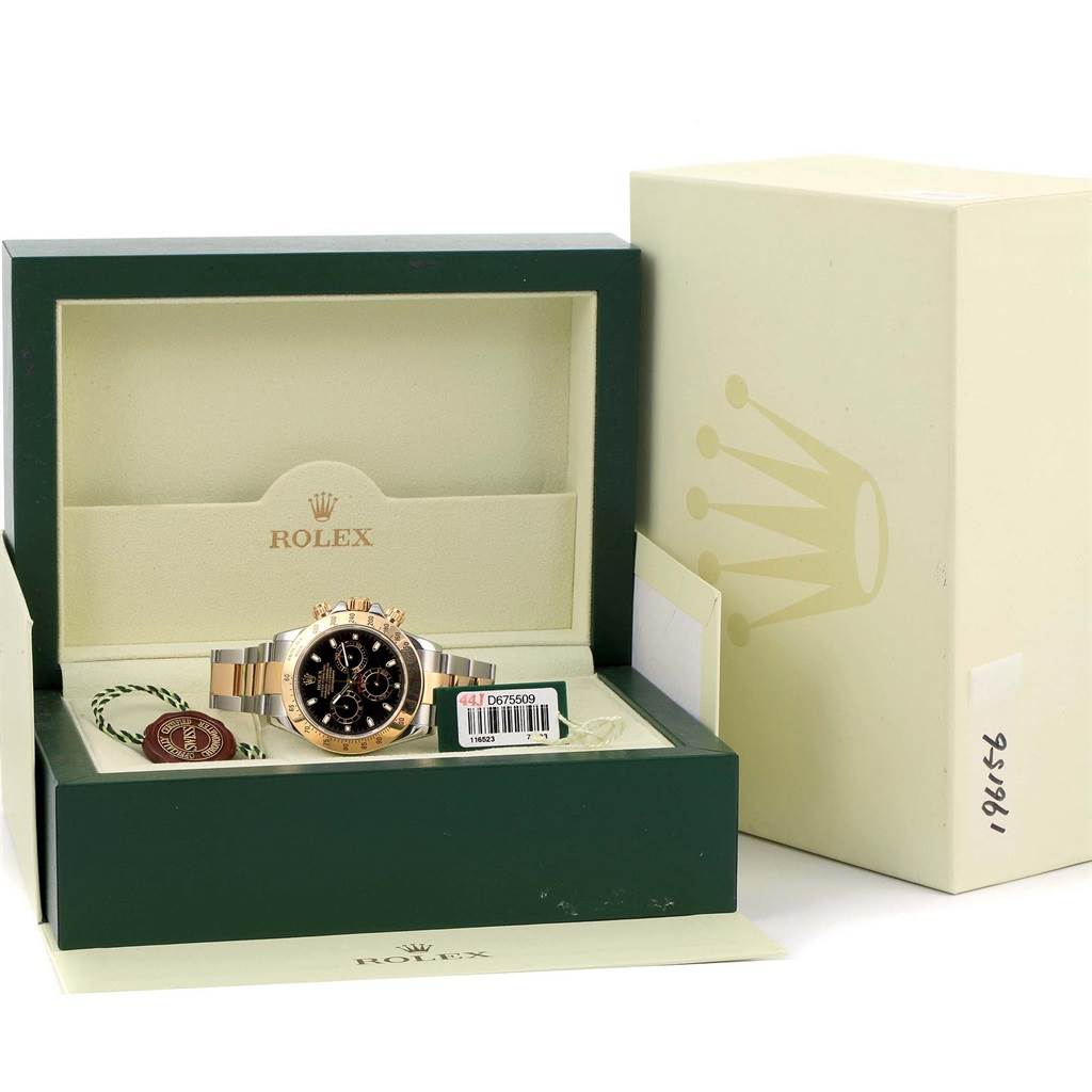 The image shows a Rolex Daytona 116523 Men's Steel and Gold (two tone) Black Dial 116523 Men's Steel and Gold (two tone) Black Dial watch inside its green box with tags, warranty card, and exterior packaging.