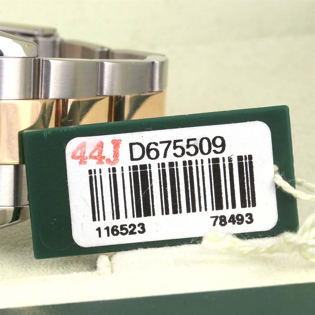 This image shows the bracelet of a Rolex Daytona 116523 Men's Steel and Gold (two tone) Black Dial 116523 Men's Steel and Gold (two tone) Black Dial watch with a green tag displaying a serial number.