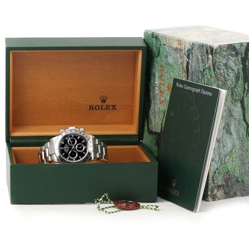 The Rolex Daytona 116520 Men's Stainless Steel Black Dial 116520 Men's Stainless Steel Black Dial watch is shown in an open box, accompanied by its booklet and outer packaging.