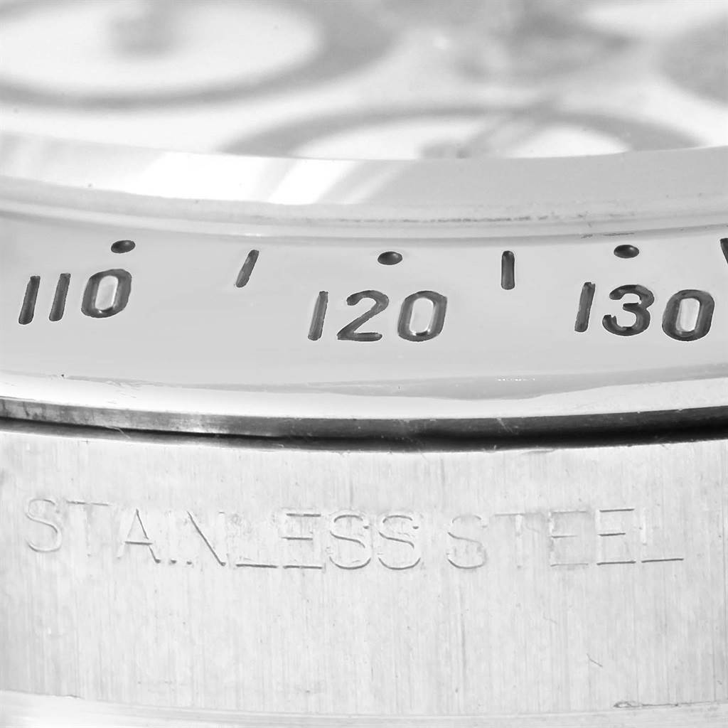 The image shows a close-up of the bezel and part of the case back of a Rolex Daytona 116520 Men's Stainless Steel White Dial 116520 Men's Stainless Steel White Dial, highlighting the stainless steel engraving and tachymeter scale.