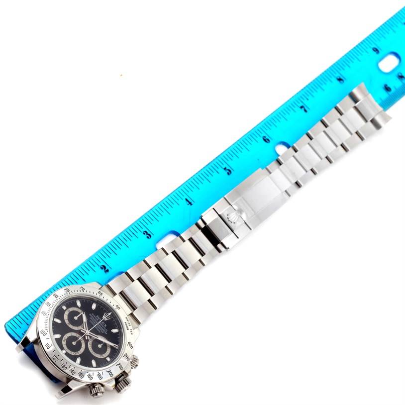 This Rolex Daytona 116520 Men's Stainless Steel Black Dial 116520 Men's Stainless Steel Black Dial watch is shown from an overhead angle, displaying its face, bezel, and full metal bracelet alongside a ruler for scale.