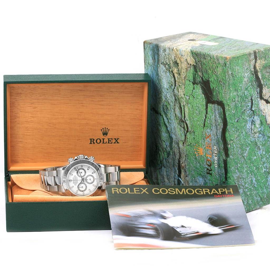 The image shows a Rolex Daytona 116520 Men's Stainless Steel White Dial 116520 Men's Stainless Steel White Dial watch placed in its box, along with the outer packaging and a booklet titled "Rolex Cosmograph Daytona."