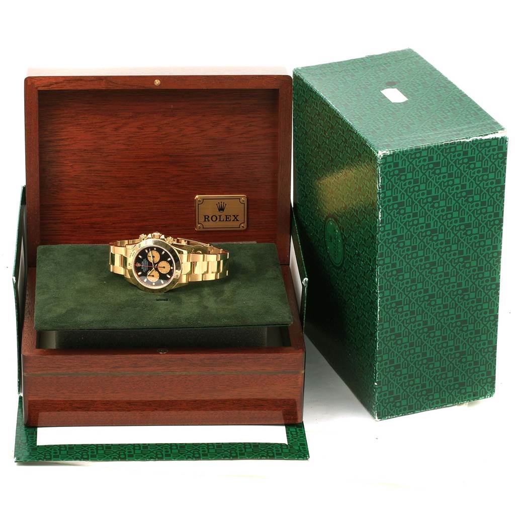 The image shows a Rolex Daytona 116528 Men's Yellow Gold Black Dial 116528 Men's Yellow Gold Black Dial watch placed inside an open Rolex wooden box, with the outer green packaging visible to the side.