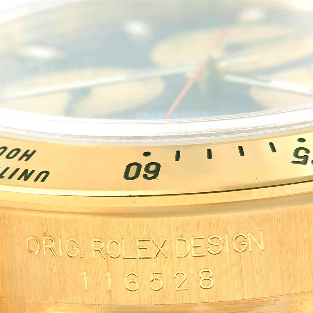 The image shows a close-up view of the Rolex Daytona 116528 Men's Yellow Gold Black Dial 116528 Men's Yellow Gold Black Dial's bezel and casing, highlighting the inscription and model number 116528.