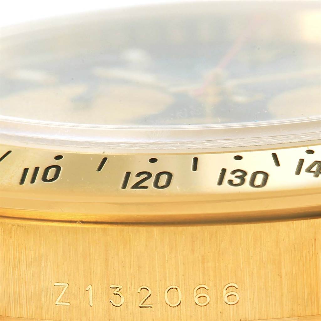 Close-up of a Rolex Daytona 116528 Men's Yellow Gold Black Dial 116528 Men's Yellow Gold Black Dial watch bezel and case, showing the tachymeter scale and part of the serial number 'Z132066.'