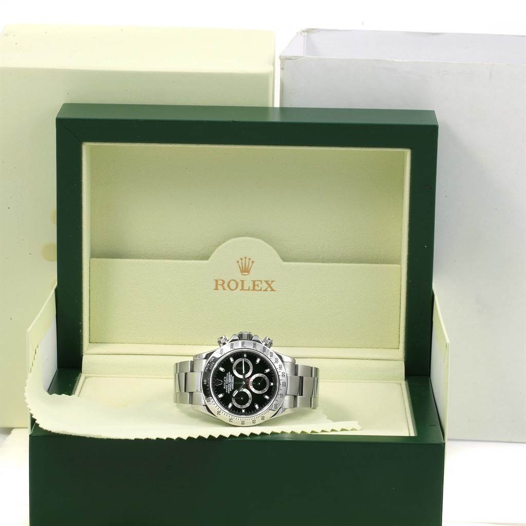 The image shows a front view of a Rolex Daytona 116520 Men's Stainless Steel Black Dial 116520 Men's Stainless Steel Black Dial watch inside its green and beige case.