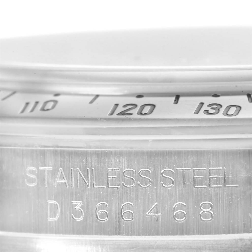 This close-up image of a Rolex Daytona 116520 Men's Stainless Steel Black Dial 116520 Men's Stainless Steel Black Dial watch shows part of the bezel and the stainless steel case with a serial number.