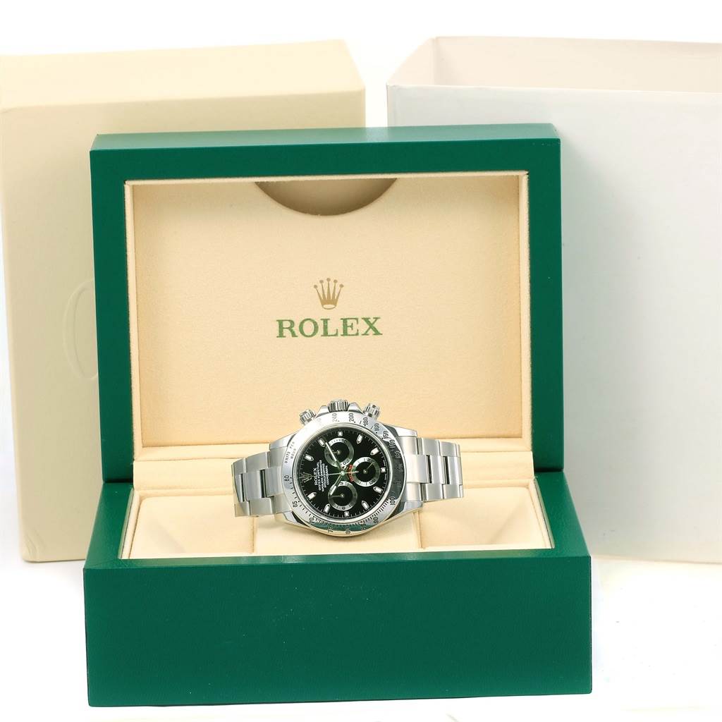 The Rolex Daytona 116520 Men's Stainless Steel Black Dial 116520 Men's Stainless Steel Black Dial watch is displayed in its green and cream-colored box, showing the front of the watch with its silver bracelet.