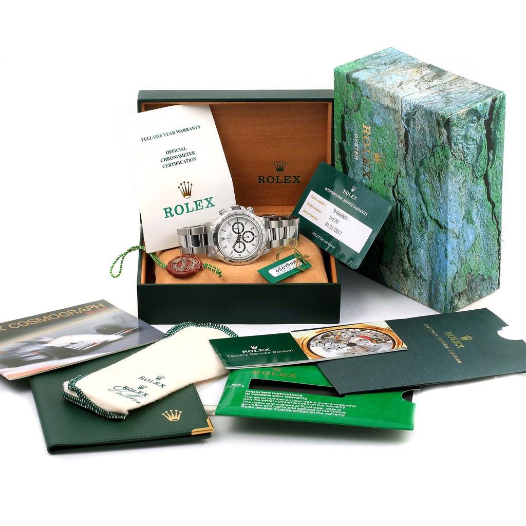 This image shows a Rolex Daytona 16520 Men
s Stainless Steel White Dial 16520 Men
s Stainless Steel White Dial watch in its box alongside documentation, a warranty card, and accessories displayed from a semi-aerial angle.