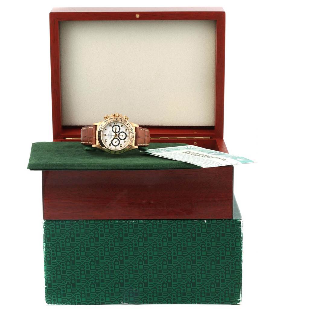The Rolex Daytona 16518 Men's Yellow Gold White Dial 16518 Men's Yellow Gold White Dial watch is displayed front-on in an open box, alongside documentation.