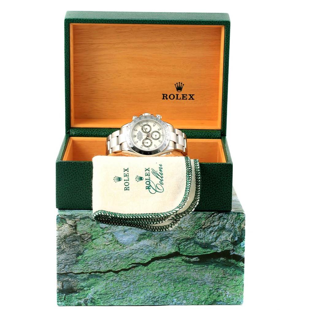 The image shows a Rolex Daytona 116520 Men's Stainless Steel White Dial 116520 Men's Stainless Steel White Dial watch front-on in an open green and wooden box with a Rolex cloth in front of it.