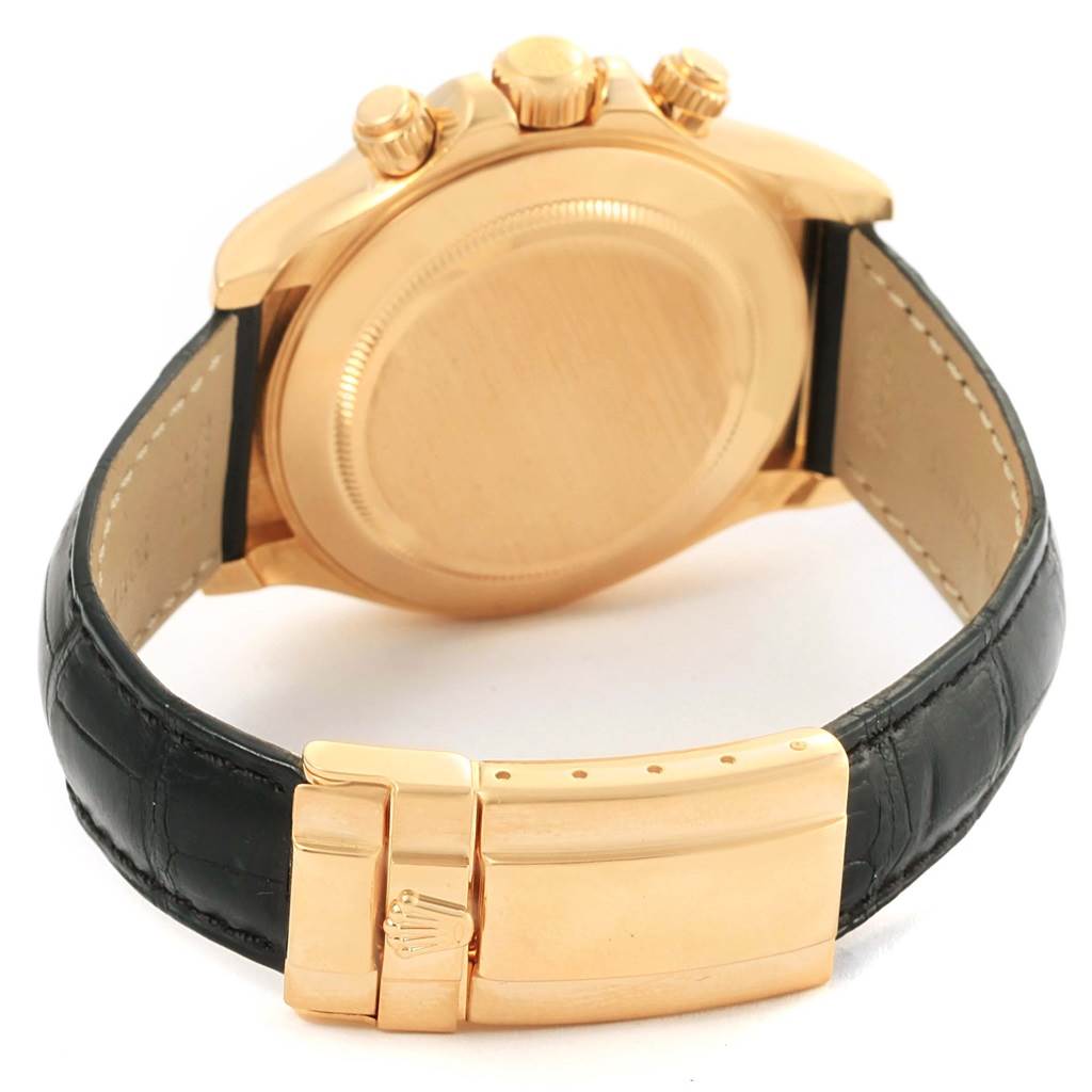 This image shows the back case, crown, pushers, and clasp of a Rolex Daytona 116518 Men's Yellow Gold White Dial 116518 Men's Yellow Gold White Dial watch with a black leather strap.