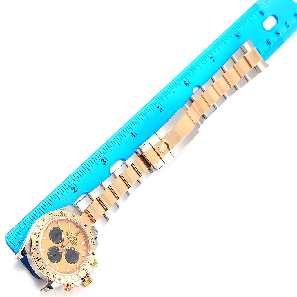 The image shows a Rolex Daytona 116523 Men's Steel and Gold (two tone) Champagne Dial 116523 Men's Steel and Gold (two tone) Champagne Dial watch laid flat with a blue ruler for measurement, displaying the dial and bracelet.