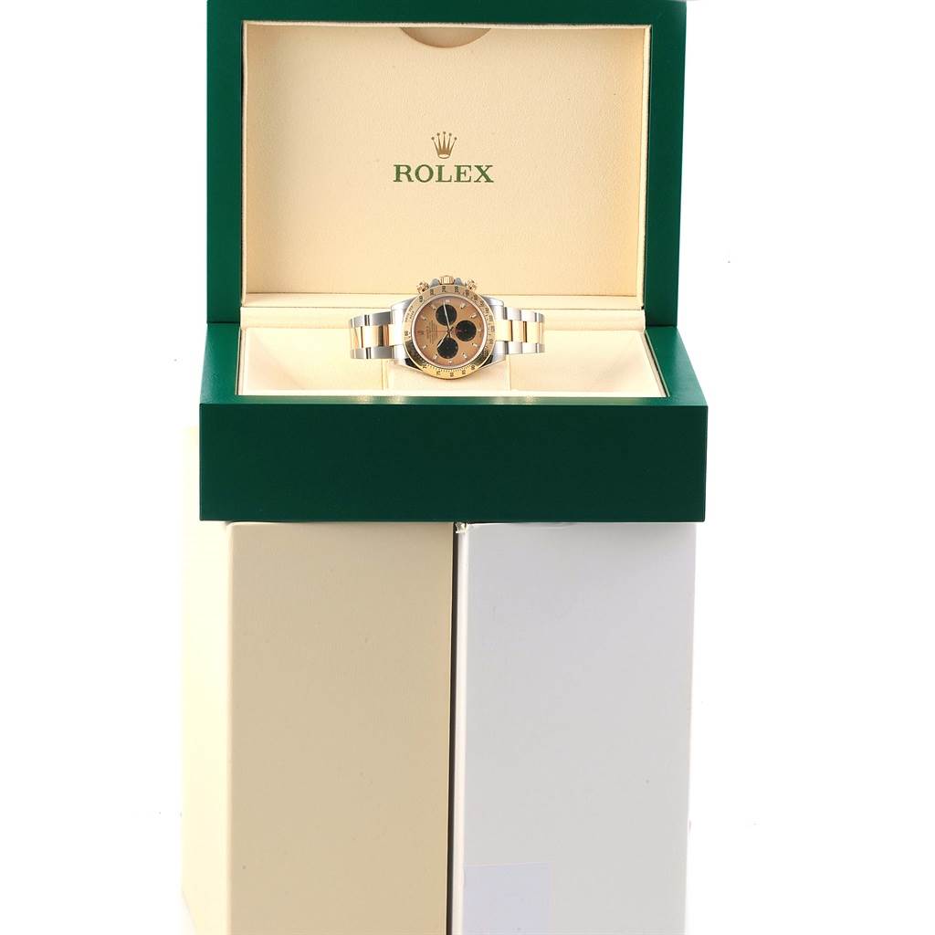 The Rolex Daytona 116523 Men's Steel and Gold (two tone) Champagne Dial 116523 Men's Steel and Gold (two tone) Champagne Dial watch is displayed front-on in its open green and beige box.