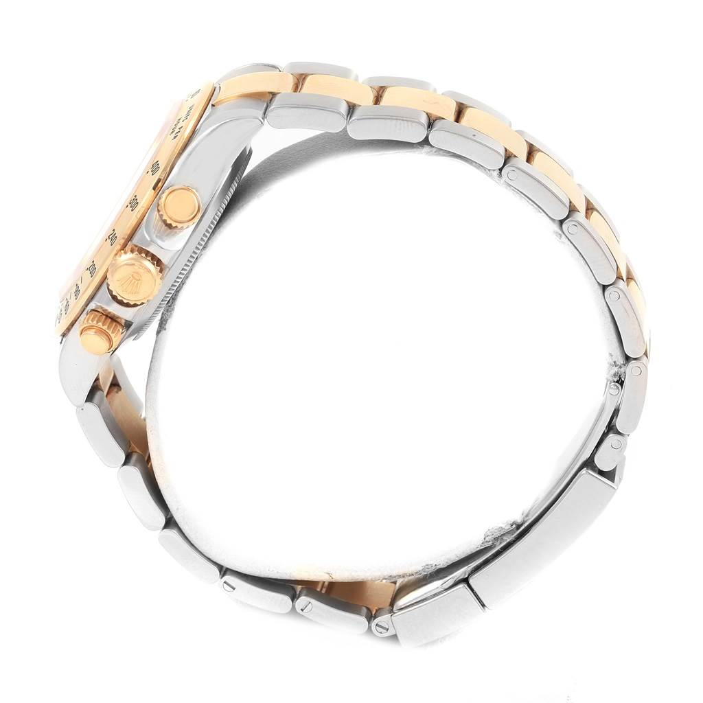 This side view of the Rolex Daytona 116523 Men's Steel and Gold (two tone) Black Dial 116523 Men's Steel and Gold (two tone) Black Dial watch shows the bezel, crown, pushers, and two-tone bracelet.