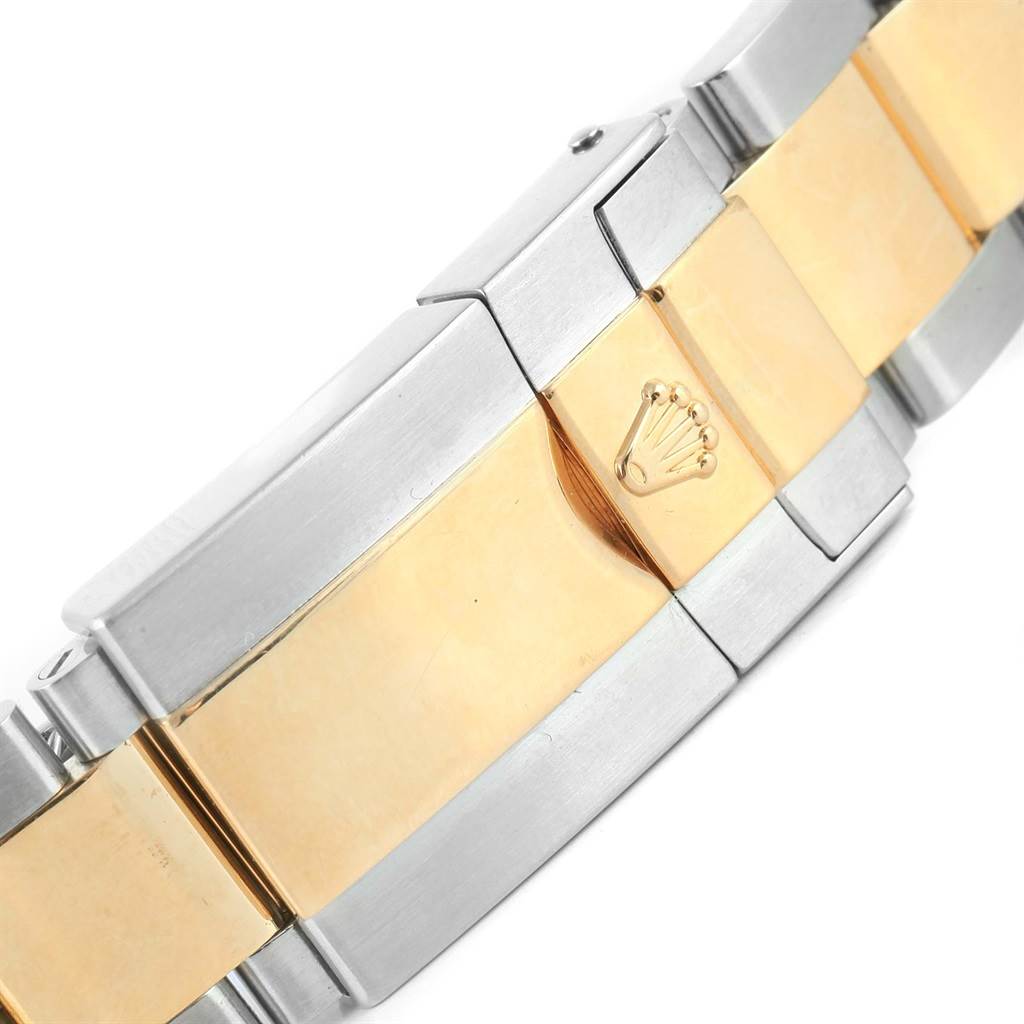 The image shows a close-up of the bracelet clasp of a Rolex Daytona 116523 Men's Steel and Gold (two tone) Black Dial 116523 Men's Steel and Gold (two tone) Black Dial watch, highlighting the brand's logo in the center.