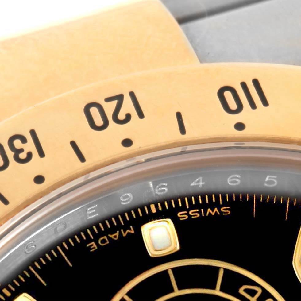 This close-up image shows the bezel and dial of a Rolex Daytona 116523 Men's Steel and Gold (two tone) Black Dial 116523 Men's Steel and Gold (two tone) Black Dial watch, highlighting the numeric markers and part of the minute track.