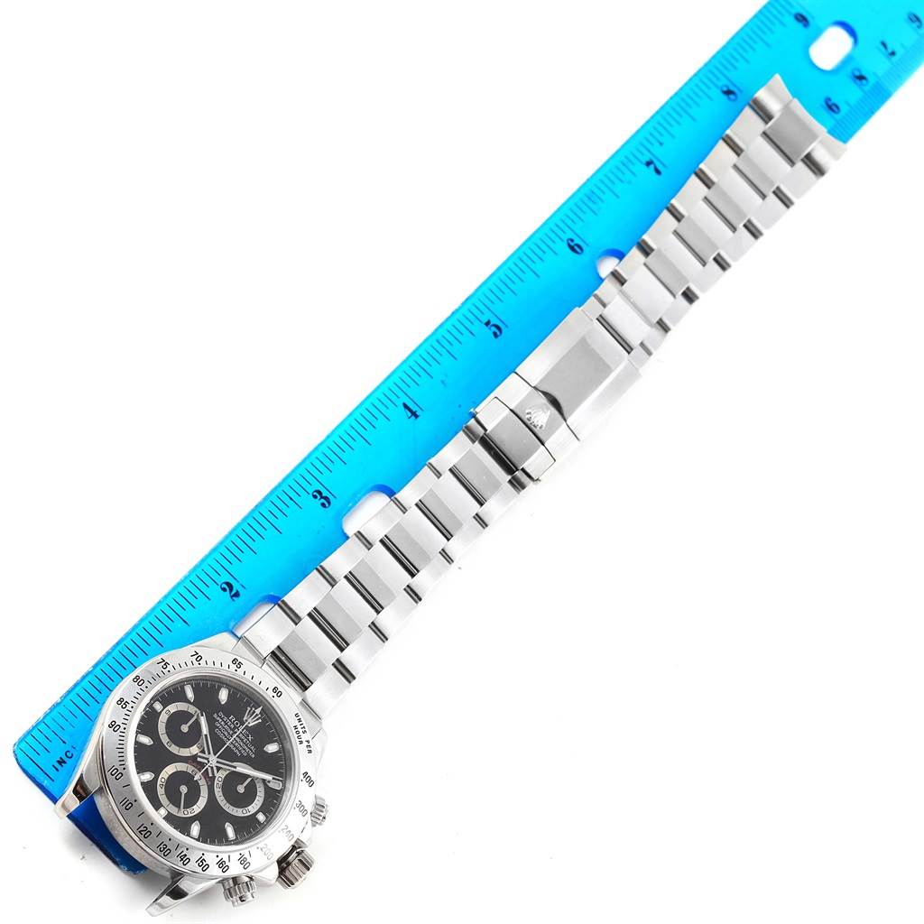 The Rolex Daytona 116520 Men's Stainless Steel Black Dial 116520 Men's Stainless Steel Black Dial watch is shown from a top-down angle, highlighting the face, bezel, band, clasp, and a ruler for scale.