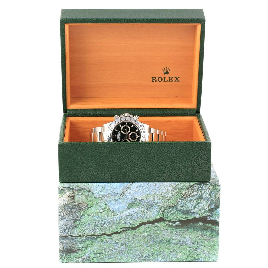 The Rolex Daytona 116520 Men's Stainless Steel Black Dial 116520 Men's Stainless Steel Black Dial watch is shown front-on, inside an open green box with the Rolex logo visible.
