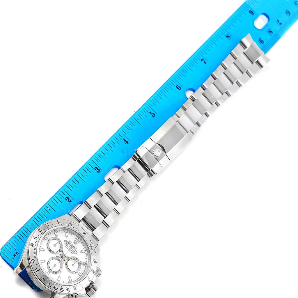 The image shows a top-down view of a Rolex Daytona 116520 Men's Stainless Steel White Dial 116520 Men's Stainless Steel White Dial watch alongside a blue ruler, displaying the watch face and metal strap.