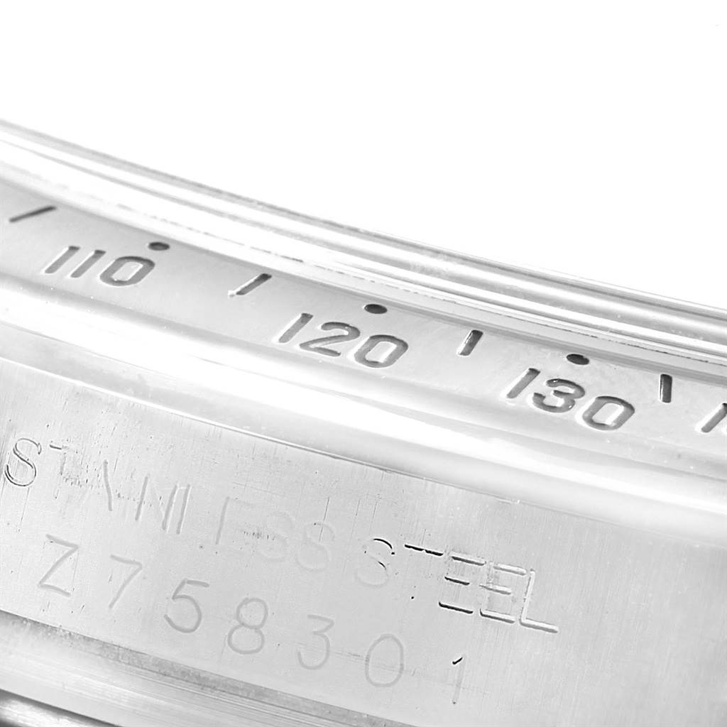 The image shows the bezel and part of the caseback of a Rolex Daytona 116520 Men's Stainless Steel White Dial 116520 Men's Stainless Steel White Dial watch, highlighting the tachymeter scale and engraved serial number.