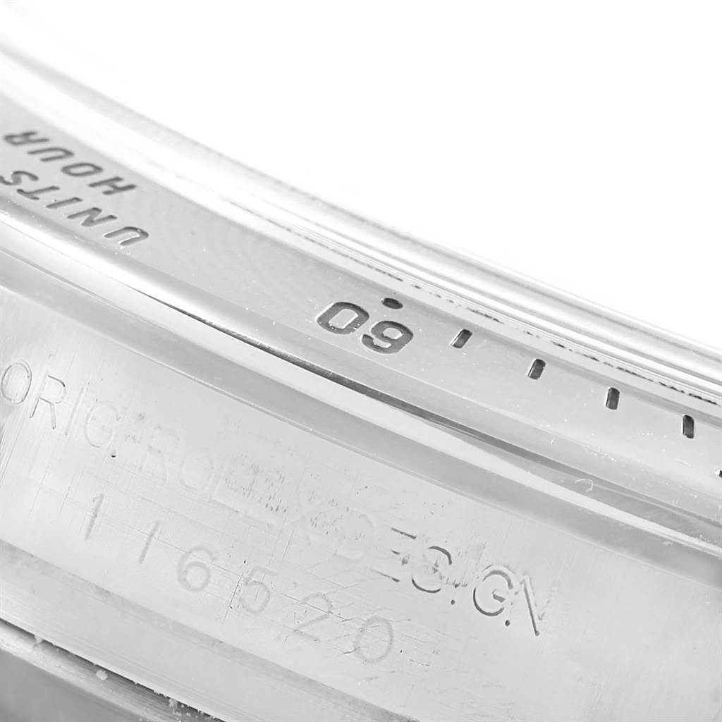 This close-up image shows the edge of the bezel and part of the engraved case of a Rolex Daytona 116520 Men's Stainless Steel White Dial 116520 Men's Stainless Steel White Dial watch.