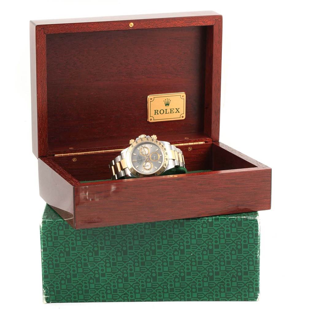 The Rolex Daytona 116523 Men's Steel and Gold (two tone) Grey Dial 116523 Men's Steel and Gold (two tone) Grey Dial watch is displayed in an open wooden box, showing its face and bracelet.