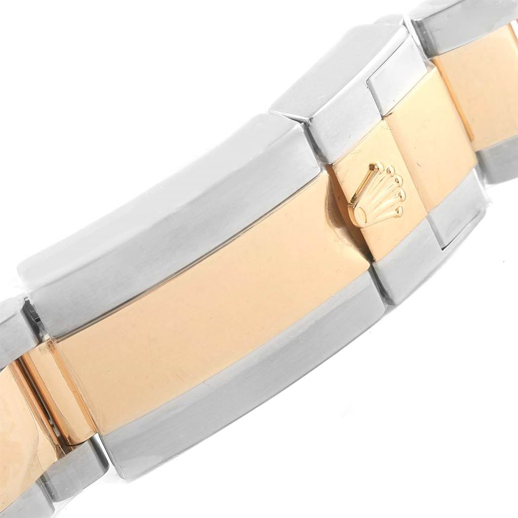 The image shows a close-up of the bracelet clasp of a Rolex Daytona 116523 Men's Steel and Gold (two tone) White Dial 116523 Men's Steel and Gold (two tone) White Dial watch, featuring a two-tone design and the Rolex logo.