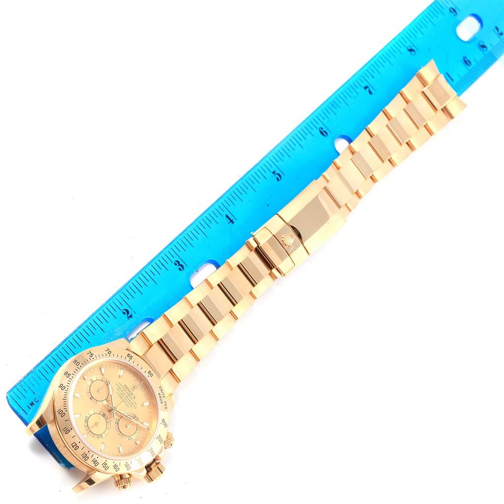 The image shows a Rolex Daytona 116528 Men's Yellow Gold Champagne Dial 116528 Men's Yellow Gold Champagne Dial watch laid flat with a blue ruler for scale, displaying the face and bracelet.