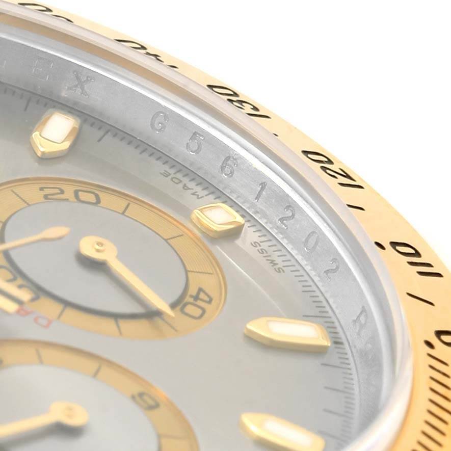 The image shows a close-up of a Rolex Daytona 116523 Men's Steel and Gold (two tone) Grey Dial 116523 Men's Steel and Gold (two tone) Grey Dial watch's bezel, dial, and sub-dials at a tilted angle.