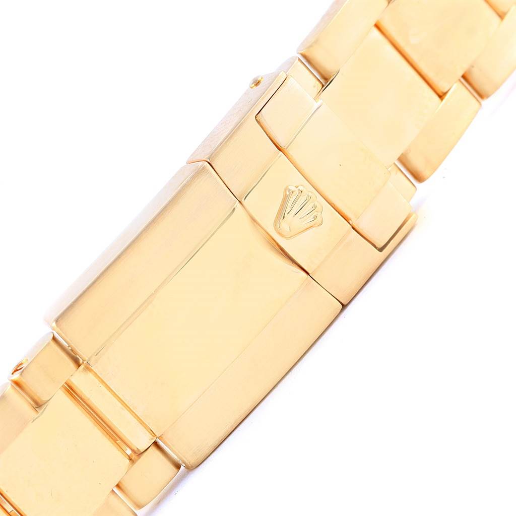 The image shows a close-up of the gold bracelet clasp with the Rolex logo on a Daytona model watch.