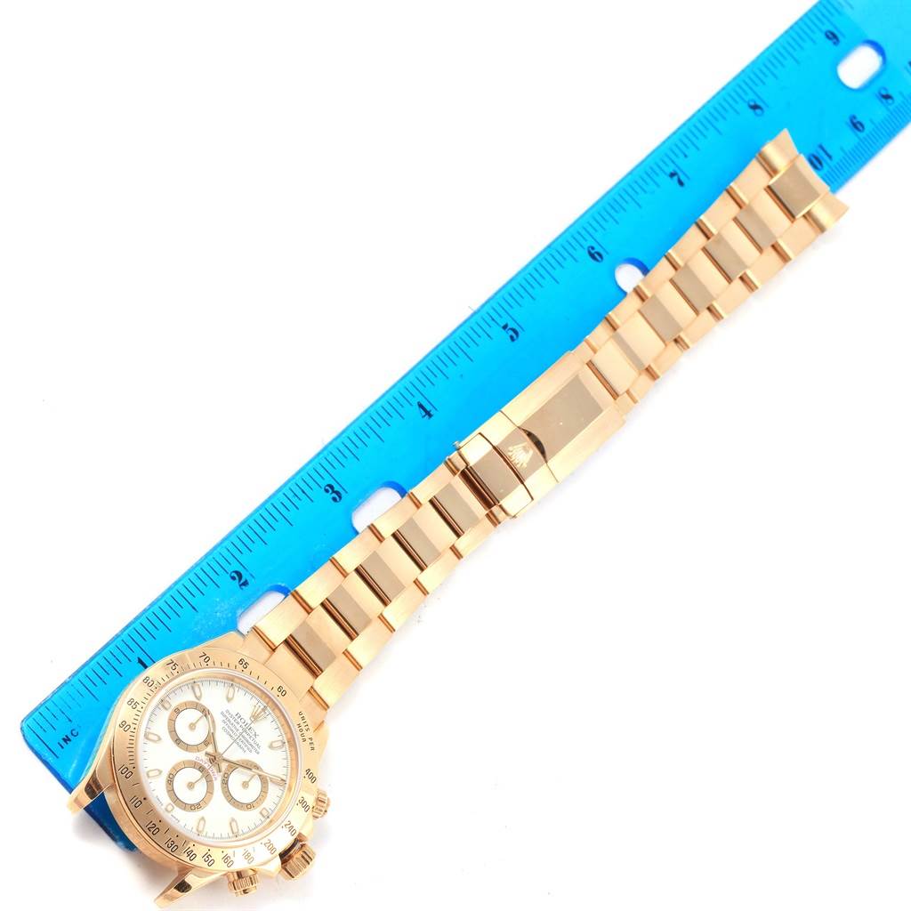 This image shows a Rolex Daytona 116528 Men's Yellow Gold White Dial 116528 Men's Yellow Gold White Dial watch at an overhead angle, featuring the face, bezel, and bracelet with a blue ruler for scale.