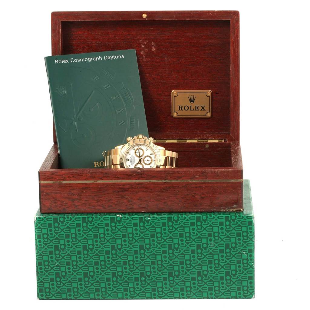 The image shows a Rolex Daytona 116528 Men's Yellow Gold White Dial 116528 Men's Yellow Gold White Dial watch and its booklet in an open wooden Rolex box.