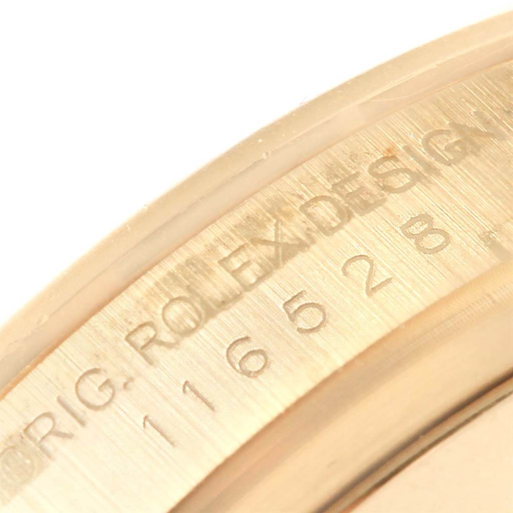 This close-up image shows the engraved inscription and serial number on the edge of the bezel of a Rolex Daytona 116528 Men's Yellow Gold White Dial 116528 Men's Yellow Gold White Dial model watch.