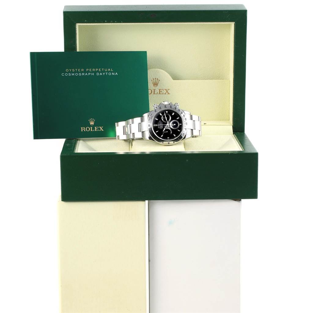 The image shows a Rolex Daytona 116520 Men's Stainless Steel Black Dial 116520 Men's Stainless Steel Black Dial watch and its green box, viewed from the front, with the instruction manual visible.